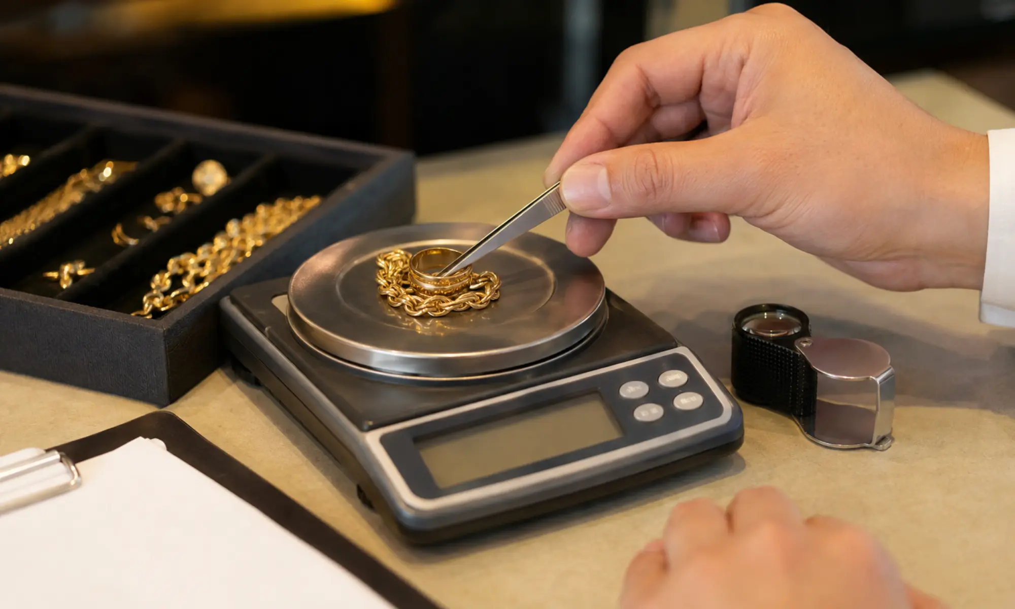 Goldschmuck wird mit Pinzette auf Präzisionswaage beim Juwelier geprüft